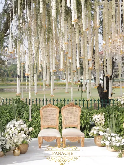 Another view of the couple's seating, framed by lush white floral arrangements in golden vases. The design is clean, classic, and timeless.