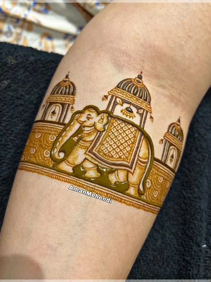 A close-up of a royal elephant motif on the arm. The intricate details on the elephant's saddle and the surrounding palace architecture showcase fine linework.