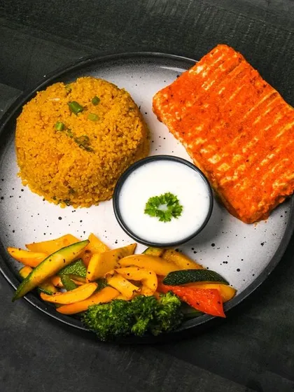 A modern Indian platter with quinoa, tandoori paneer, and sautéed vegetables. The dark background gives this healthy fusion dish a contemporary and stylish feel.