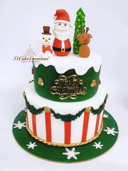 A classic two-tier Christmas cake in green, red, and white, featuring Santa, a reindeer, and a snowman on top.