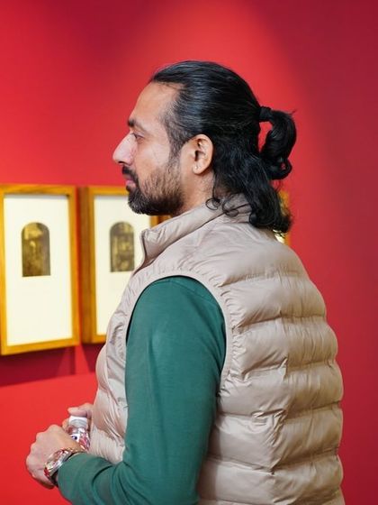 A visitor contemplates a set of framed prints, taking in the unique textures and tones of the artwork.