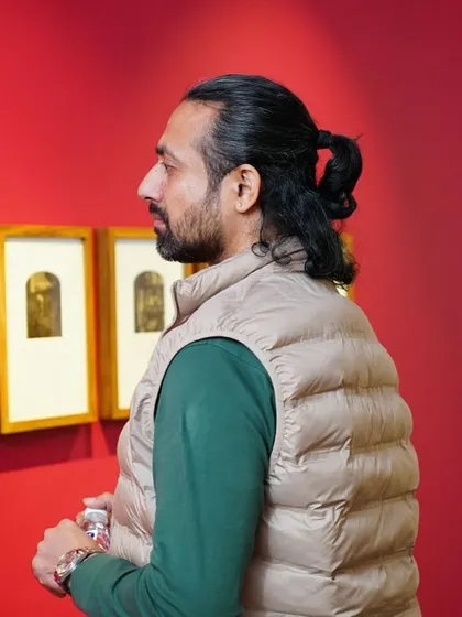 A visitor contemplates a set of framed prints, taking in the unique textures and tones of the artwork.