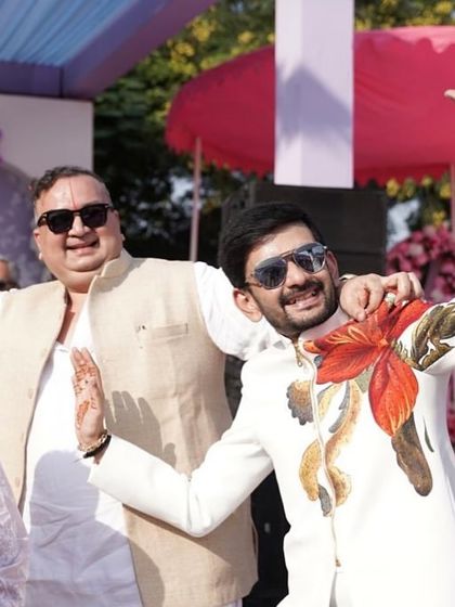 Capturing the joy of the celebration, this client is wearing another of my custom hand-painted bandhgalas. The vibrant red and orange floral artwork on the white jacket brings energy and artistic flair to his festive attire.