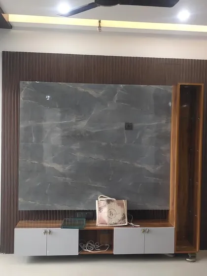 A closer look at the TV unit in a nearly completed project. The combination of a dark grey marble-finish slab and fluted wood panels creates a rich, textured backdrop for the entertainment center.