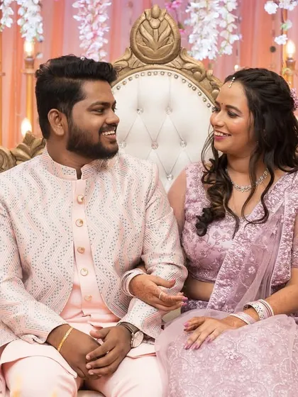 A candid shot of a couple sharing a lighthearted moment while seated on an ornate sofa at their engagement party.