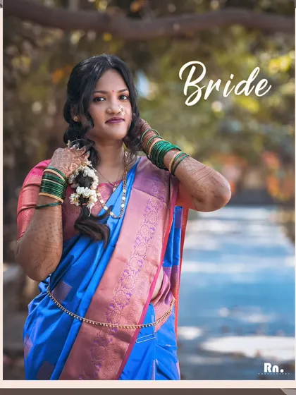 A model portfolio shot showcasing a traditional Maharashtrian bridal look. The blue and pink saree, green bangles, and classic hairstyle are captured in soft, natural light.