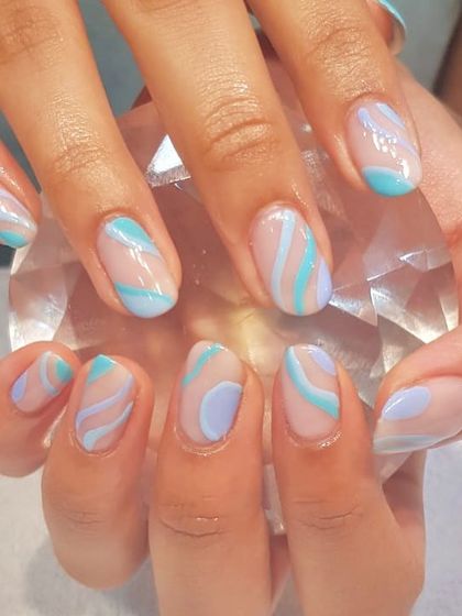 Cool, calm, and collected. This abstract nail art uses soft shades of blue and lilac in a wavy, layered design that feels both modern and serene.
