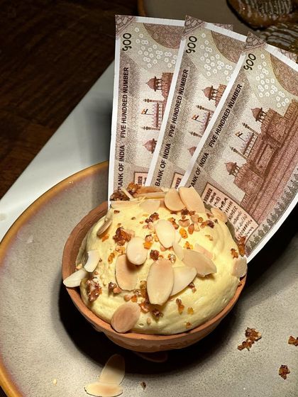 A close-up shot capturing the creamy texture of the kulfi and the crunch of the almond topping.