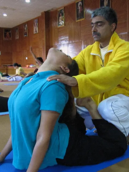 A student is guided into a deeper expression of the cobra pose. Personal corrections help students safely advance their practice and prevent injury.