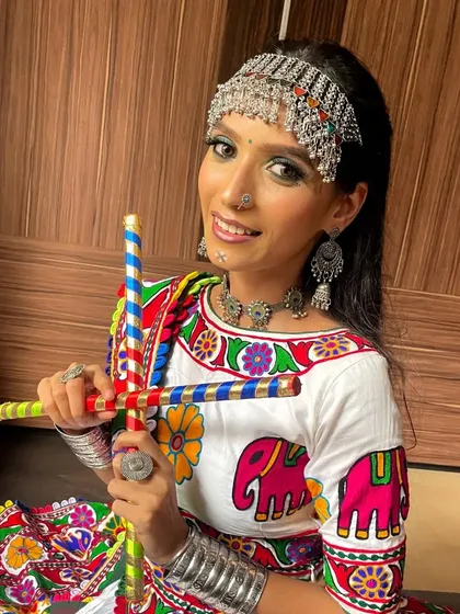 Ready for Garba! This shot features the model with dandiya sticks, capturing the joyful and energetic spirit of Navratri. The makeup is bright and long-lasting for a night of dancing.