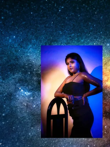 A celestial portrait with the model bathed in blue and orange light, her glitter-covered skin mimicking a starry galaxy.