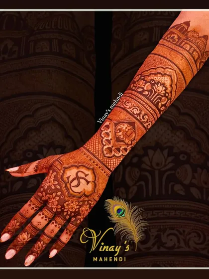 A personalized back-of-hand design featuring the couple's initials 'S' and 'G'. The design extends up the arm with architectural and elephant motifs.