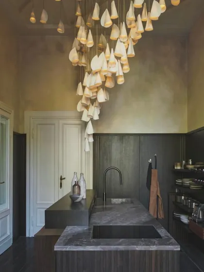A dramatic, cascading installation of the Bocci 21 series in a kitchen with high ceilings. The fixture acts as a stunning visual centerpiece in a functional space.