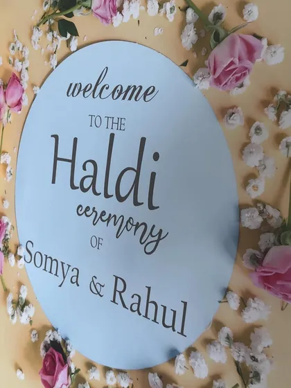 A simple and sweet welcome sign for Somya and Rahul's Haldi ceremony. The sign is decorated with scattered baby's breath and pink roses, setting a lovely tone for the event.