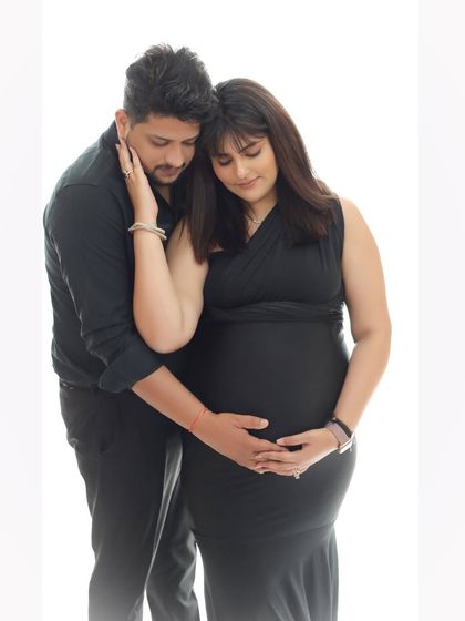 A quiet moment of connection between mother and baby. This couple portrait in classic black outfits against a bright, minimalist background is both modern and timeless.