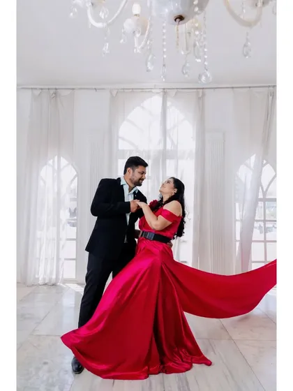 A dynamic shot of the couple dancing. The bride's flowing red gown creates a sense of movement and passion, perfect for a pre-wedding photo.