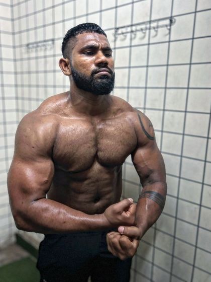 A powerful most muscular pose in the changing room. The pump is real after a brutal workout.