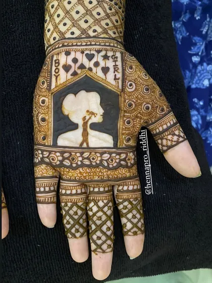 A creative take on a gender reveal henna design. This silhouette of a mother holding her baby is framed by 'Boy' and 'Girl' text, making it a centerpiece for the Godh Bharai ceremony.