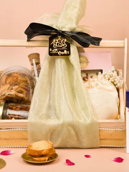 A festive gift hamper elegantly wrapped in cloth, styled with traditional lanterns and diyas. This shot focuses on the premium packaging and presentation.