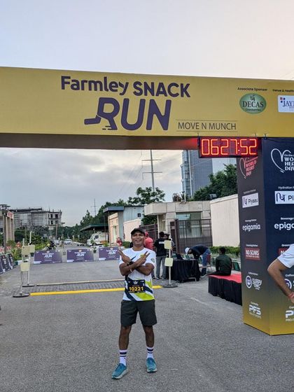 A runner posing at the finish line arch of the Farmley Snack Run. A perfect photo opportunity to commemorate the achievement.