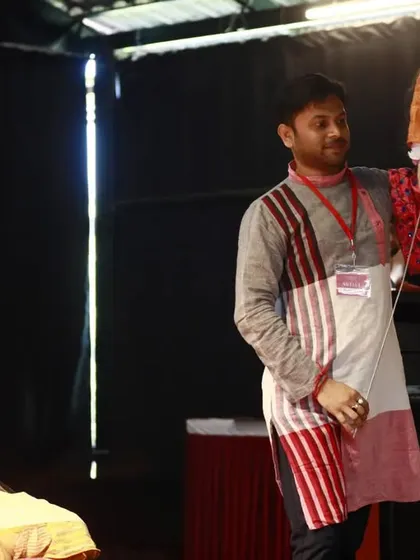 An artist demonstrates the art of rod puppetry during a conference. Unlike string puppets, these are manipulated from below using rods, a technique that allows for strong, dramatic movements.