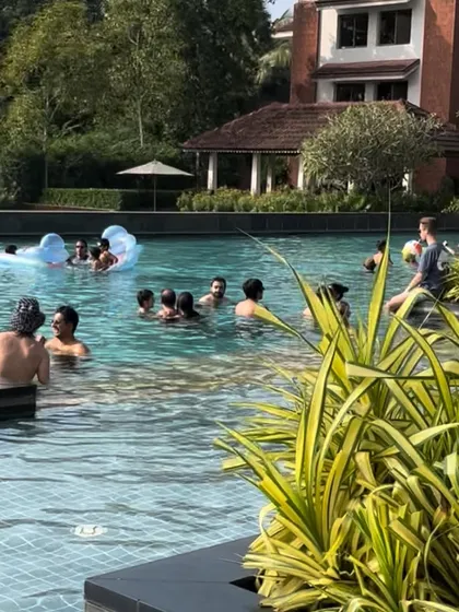 The scene at a beautiful Goa destination wedding pool party. Guests enjoying the sun and music in a stunning resort setting.