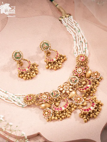 The Chaandbali Takkar Set feels like wearing a piece of moonlit celebration. Crescent silhouettes are detailed with rich red and green enamel, finished with clusters of golden beads that echo stories of festive nights and palace courtyards.