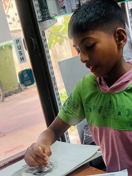 A candid shot of the young artist deeply focused on the shading process, using a blending stump to create smooth transitions in his self portrait.
