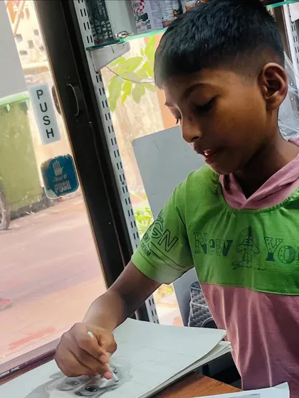 A candid shot of the young artist deeply focused on the shading process, using a blending stump to create smooth transitions in his self portrait.