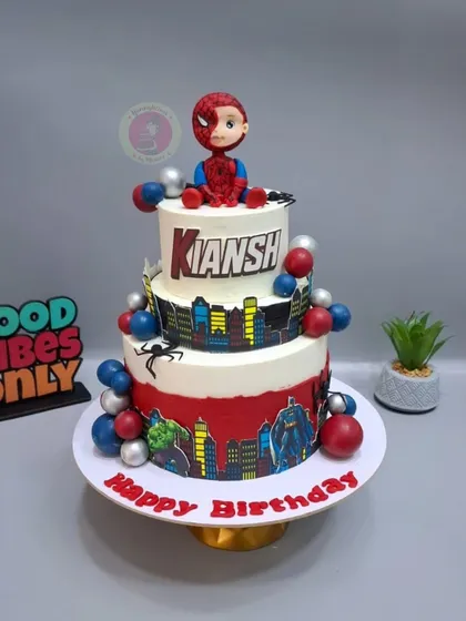 A three-tier Spiderman cake with a cute, half-masked Spidey figurine sitting on top.