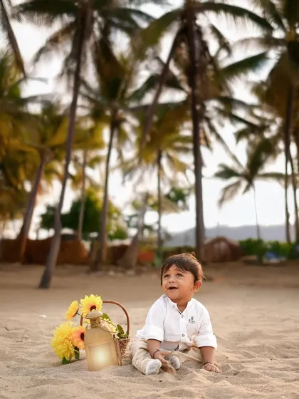 A happy baby boy sitting on the sand, with palm trees in the background. Our beach photoshoots capture the relaxed and joyful vibe of a day by the sea.