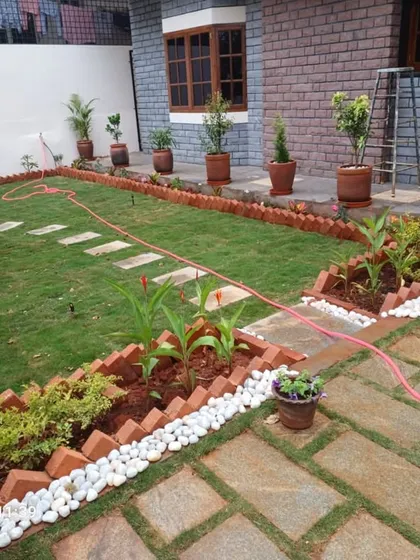 A complete residential garden installation in progress. This project showcases a new lawn, defined garden beds with brick edging, a stone pathway, and a variety of potted plants, demonstrating our end-to-end landscaping services.
