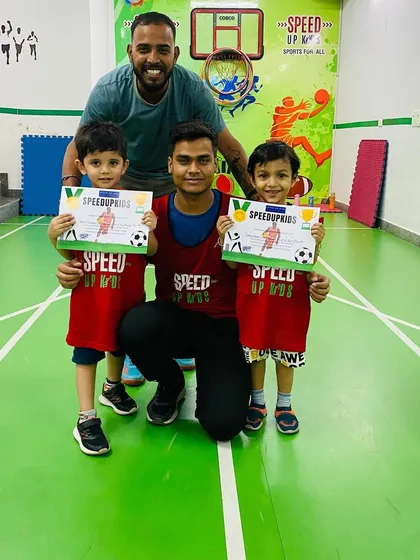 Parth and his brother, both holding their certificates, pose with their coach. We love seeing siblings grow together at our academy.