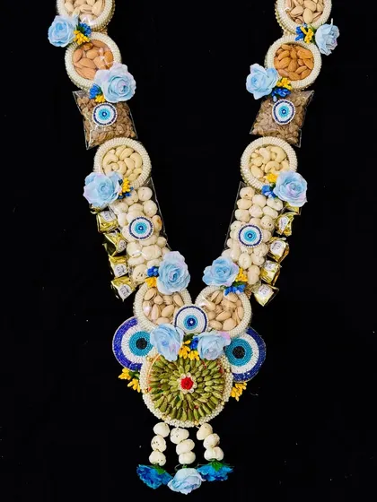 A unique Holi garland featuring an evil eye design, made with dry fruits and chocolates to wish good health and protection.