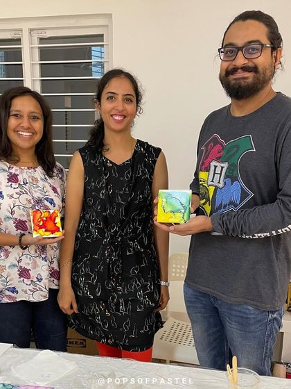 The happy couple with their instructor, showcasing the beautiful alcohol ink coasters they made during their anniversary workshop.