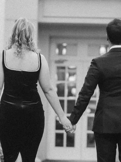 A beautiful shot of the couple walking away hand-in-hand. This black and white photo from their pre-wedding session has a classic, cinematic feel, symbolizing the start of their journey together.