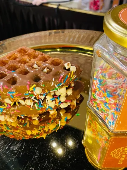 A fun and colorful waffle topped with chocolate and rainbow sprinkles, a delight for all ages.