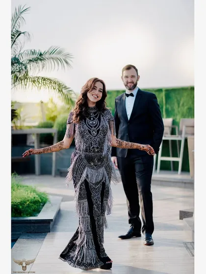 A wonderful portrait of a couple at their rooftop cocktail event. Her stunning, detailed dress and his classic tuxedo are captured in a candid moment of happiness and style.