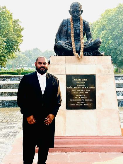 Standing by the statue of Mahatma Gandhi at the Supreme Court, a symbol of truth and non-violence.