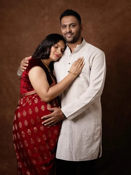 Dressed in a beautiful red saree, this mother to be rests her head on her partner's shoulder, a picture of serene love. I believe in capturing pregnancy in a way that feels true to you, including traditional attire that holds special meaning.