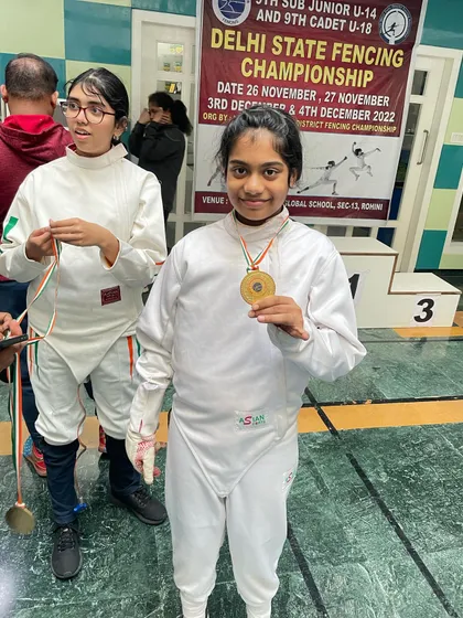 A young gold medalist in her fencing whites, right after her victory at the state championship.