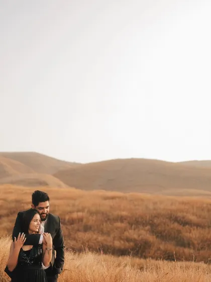A beautiful portrait with the couple framed against a vast expanse of golden fields and rolling hills, creating a sense of peace and togetherness.