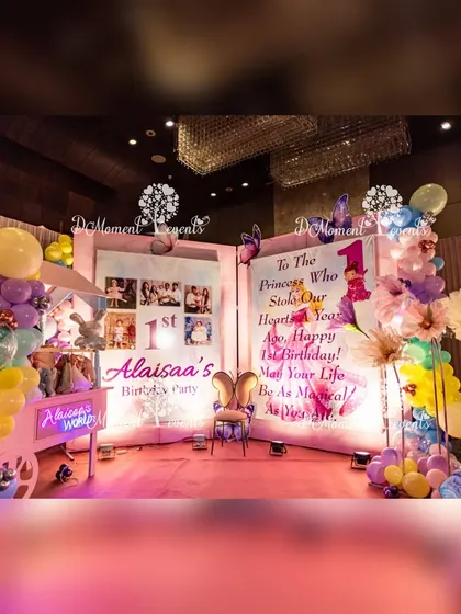 A storybook-themed photo area at a princess party. A giant open book displays photos and a heartfelt message, surrounded by balloons, a whimsical cart, and a princess cutout.