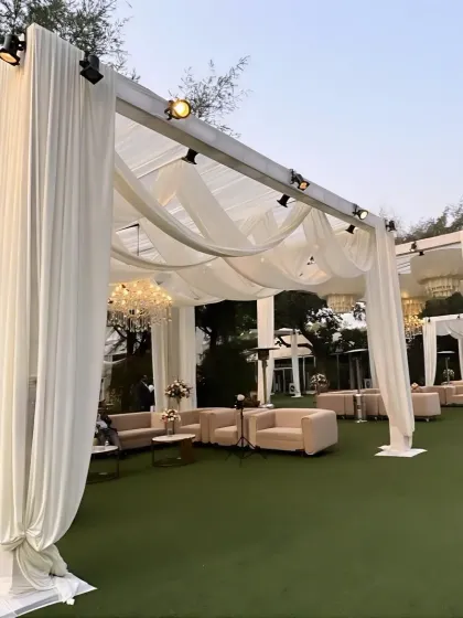 An outdoor lounge setup with elegant cabanas draped in ivory fabric, providing a comfortable and stylish space for guests to relax.