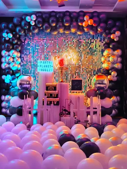 With colorful party lights, the black and silver decor transforms into a vibrant, disco-like setting. The floor is filled with balloons, adding to the fun atmosphere.