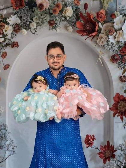 A proud father holds his twin daughters. This shot showcases the joy and love of being a new parent to two little miracles.