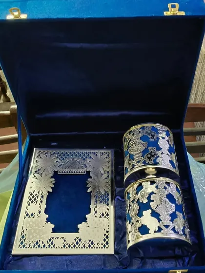 This is an example of a truly luxurious wedding invitation set. It features an intricate silver laser-cut card and matching favors, all presented in a royal blue velvet box, designed to be a treasured keepsake.