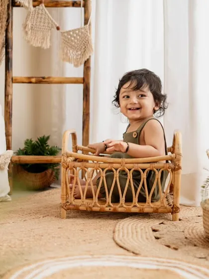 A happy boy in a boho setting for his first birthday. The natural textures of jute and wicker, along with green plants, create a calm and earthy vibe.
