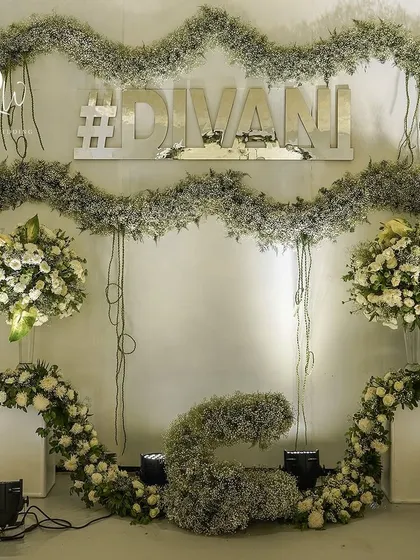 A closer look at the enchanted forest photo backdrop, with its layers of baby's breath, white roses, and the couple's custom hashtag.