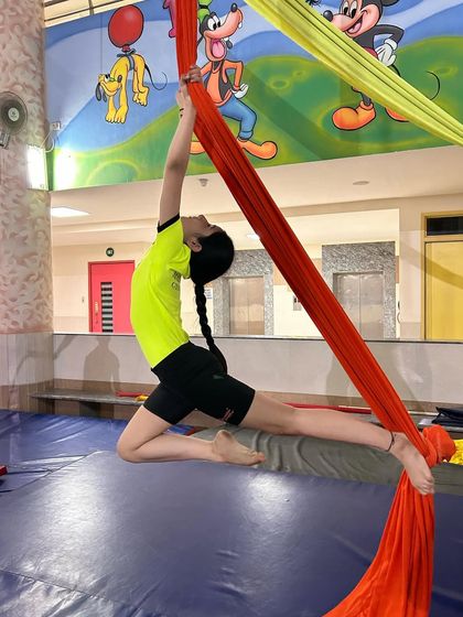 This graceful pose shows a young aerialist combining flexibility and strength as she extends into a beautiful line on the silks.